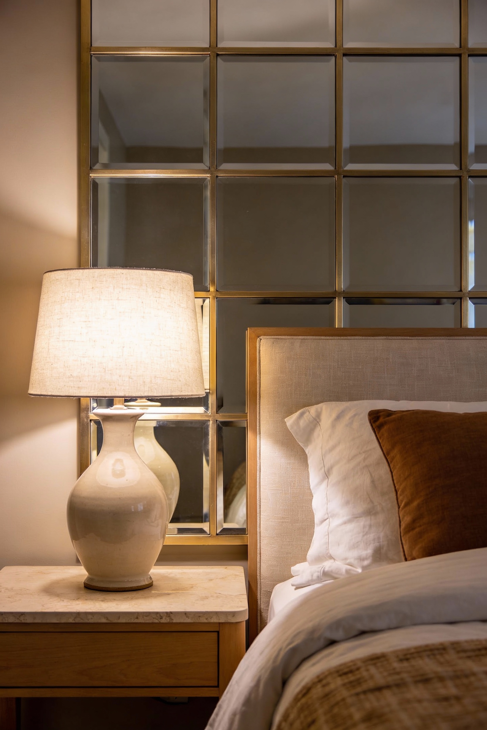 Detail close-up photorealistic cozy bedroom vignette focused on a mirrored headboard wall: large rectangular mirror pane