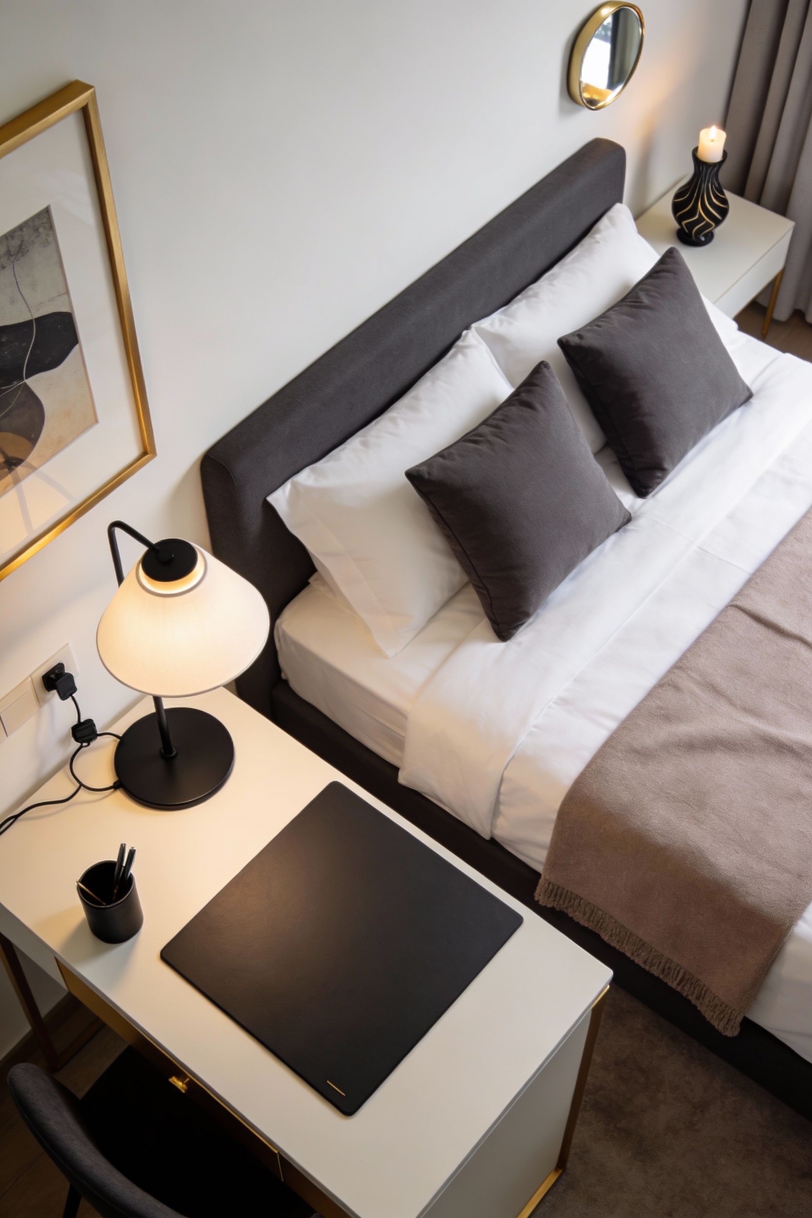 Overhead photorealistic shot of a hotel-minimal luxe hostel desk and bed edge: palette of white, charcoal, and taupe wit