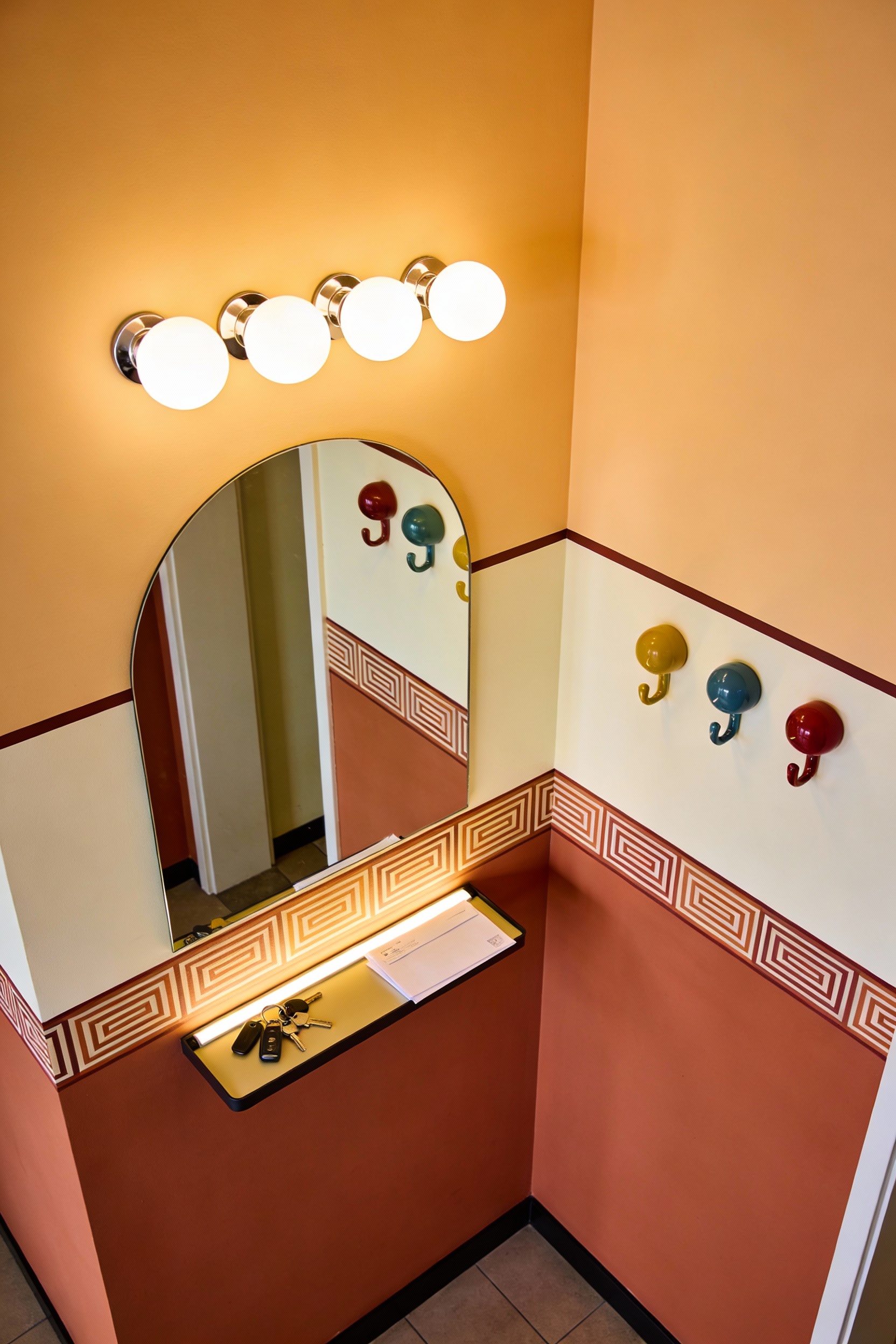 Overhead photorealistic shot of a long hallway with playful color-blocked walls (lower half clay terracotta, upper half 